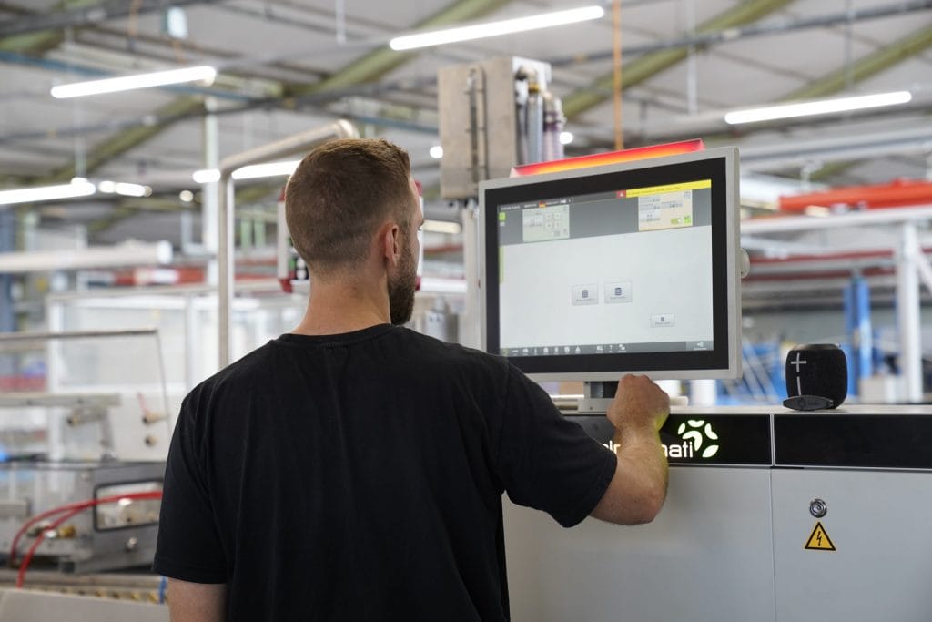 Bauprofile 5 Ein Mitarbeiter der Jansen AG steht vor einer Extrusionslinie und richtet gerade die Produktion eines Kunststoffprofils ein